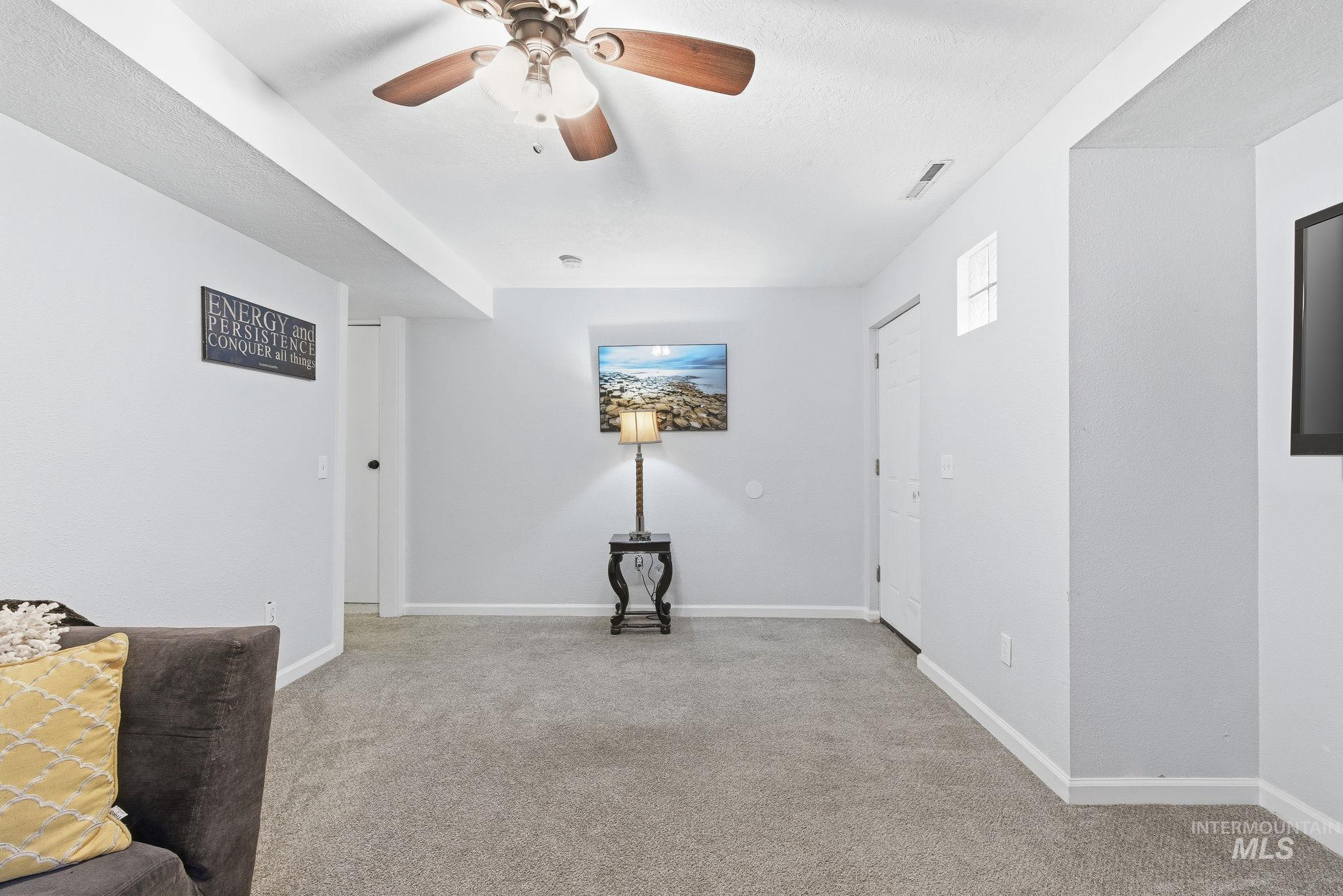 Empty room with light colored carpet and a ceiling fan