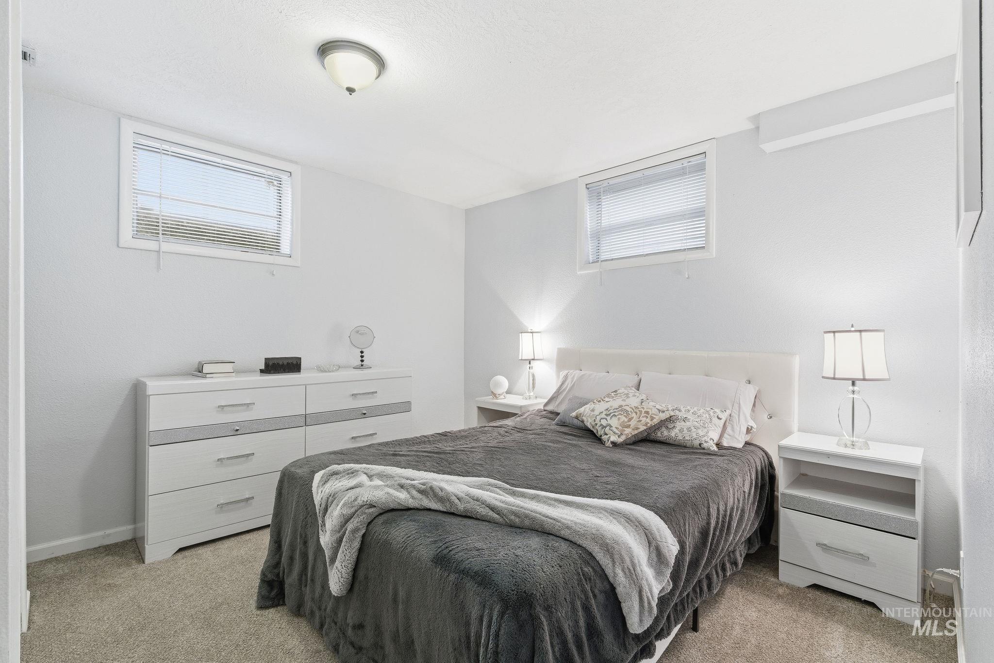 Bedroom with light colored carpet and multiple windows