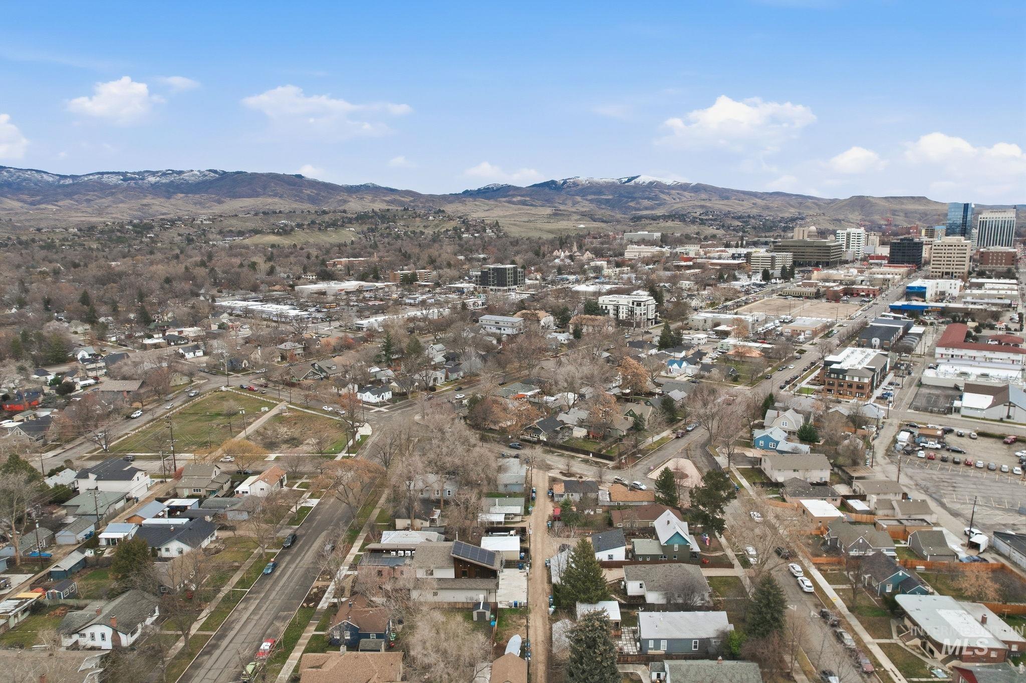 Aerial overview of property's location with a mountain backdrop and nearby suburban area