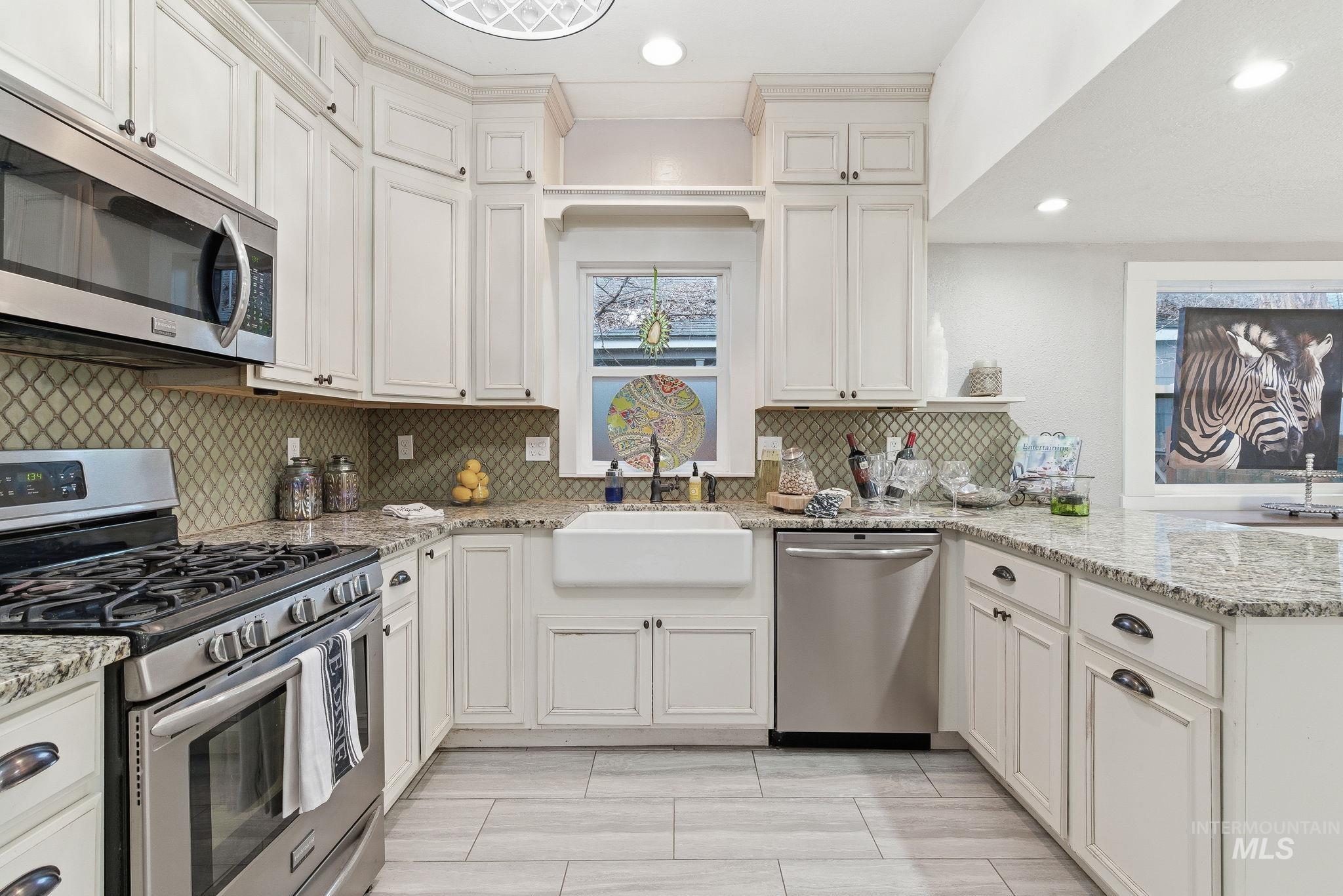 Kitchen featuring stainless steel appliances, a peninsula, light stone counters, tasteful backsplash, and recessed lighting