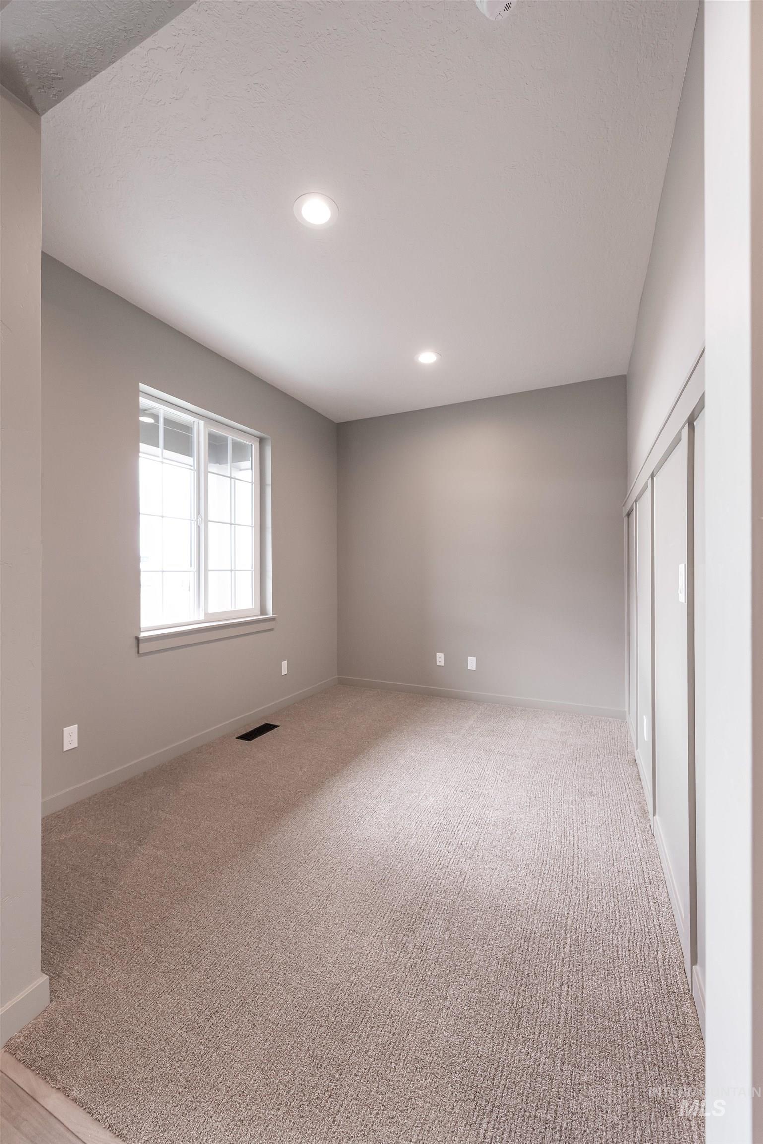 Empty room with light carpet, recessed lighting, and a textured ceiling