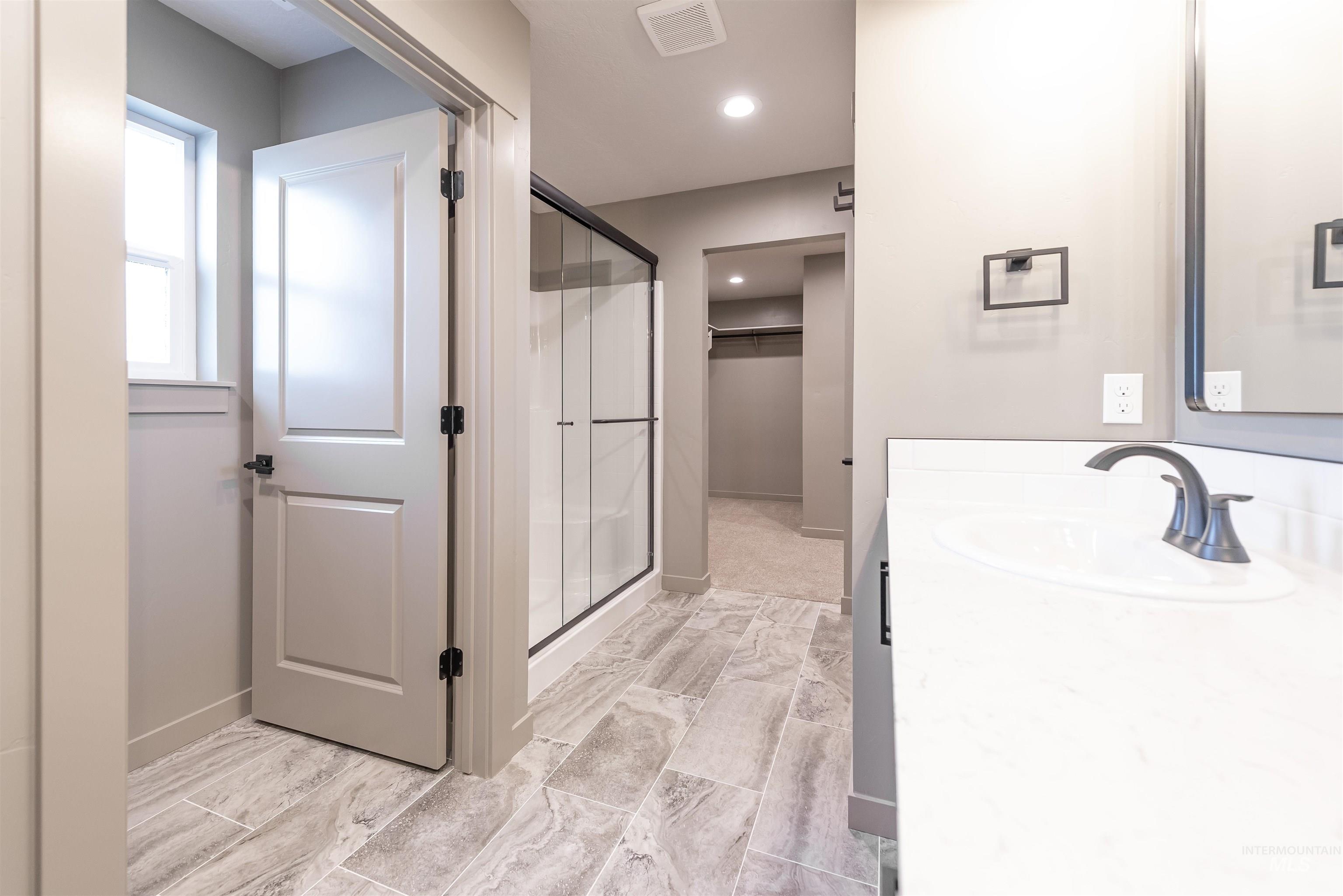 Full bath featuring a walk in closet, vanity, a shower stall, and recessed lighting