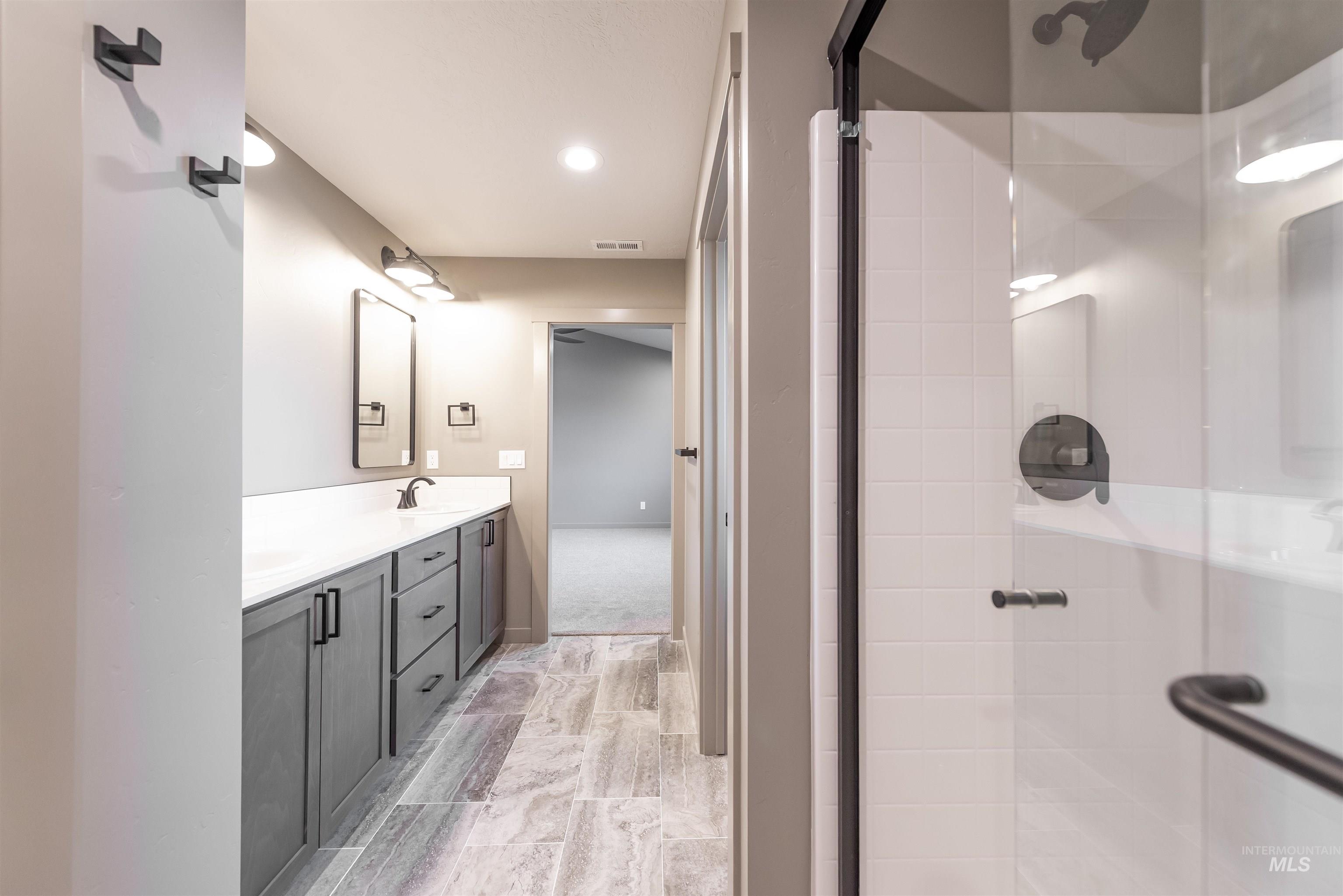 Bathroom with double vanity, a stall shower, and recessed lighting