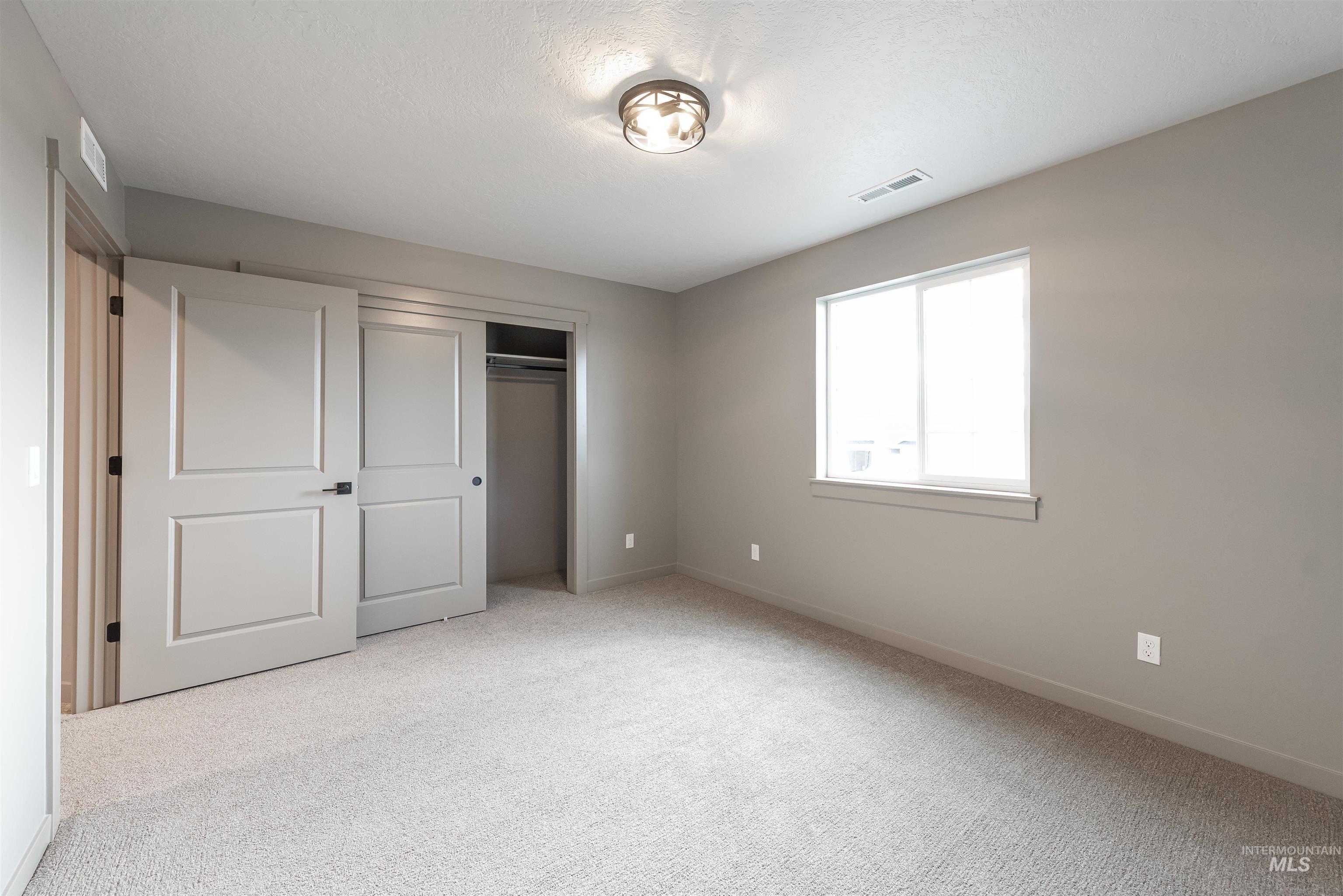 Unfurnished bedroom with light carpet and a closet