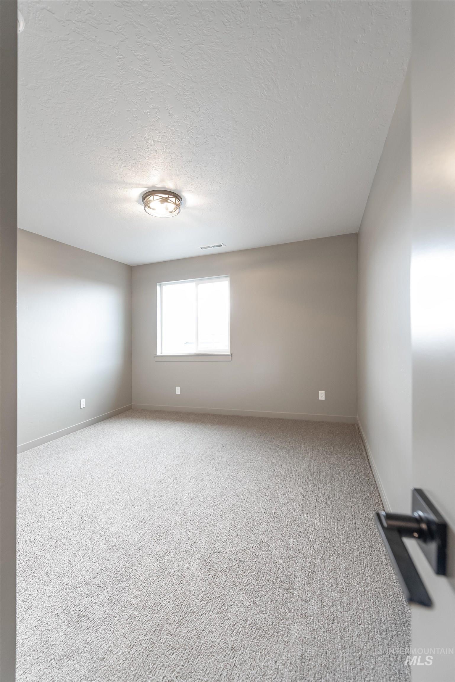 Empty room with a textured ceiling and carpet