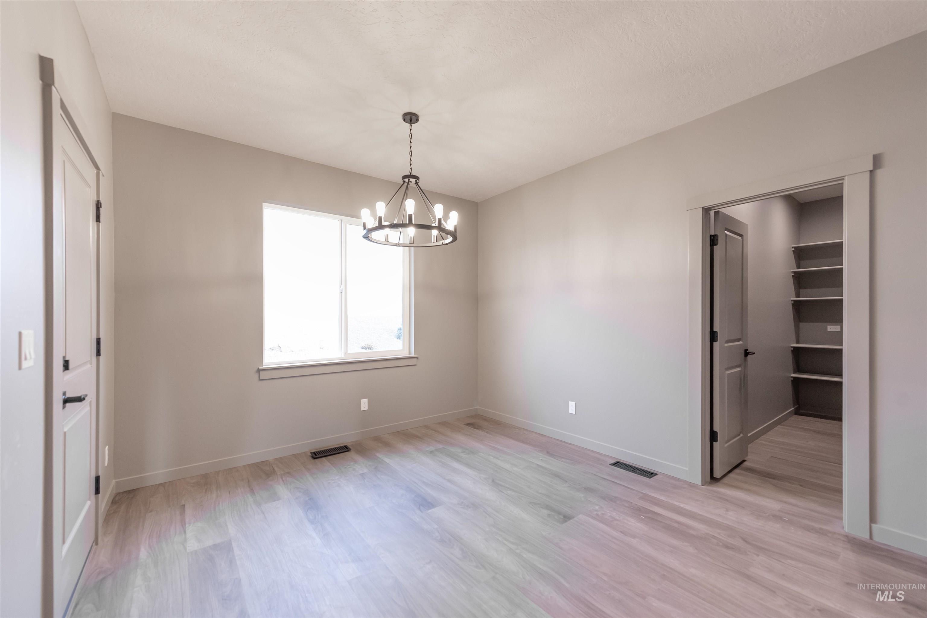Unfurnished dining area featuring light wood-style flooring and a chandelier