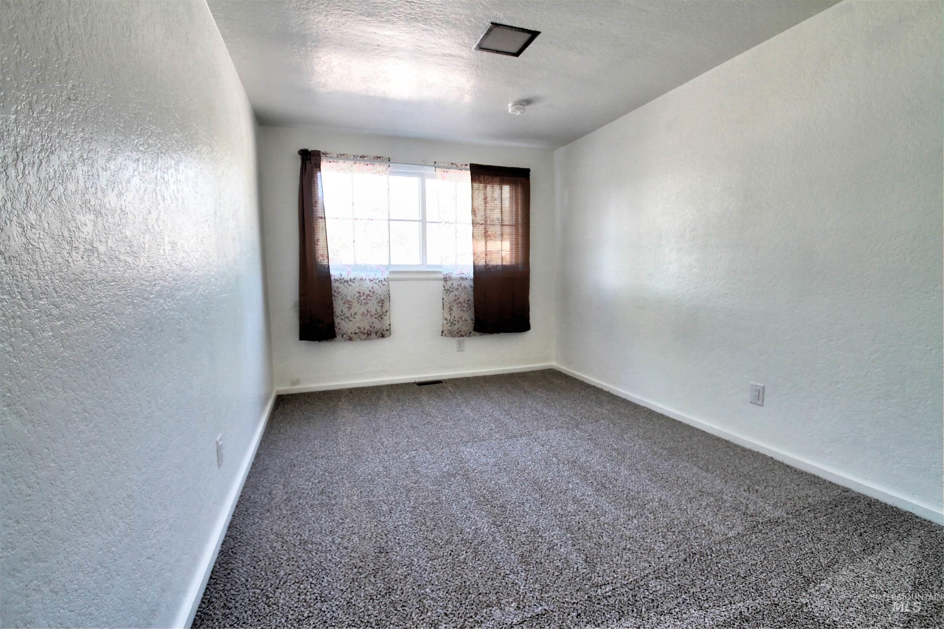 Spare room with a textured wall, a textured ceiling, and carpet floors
