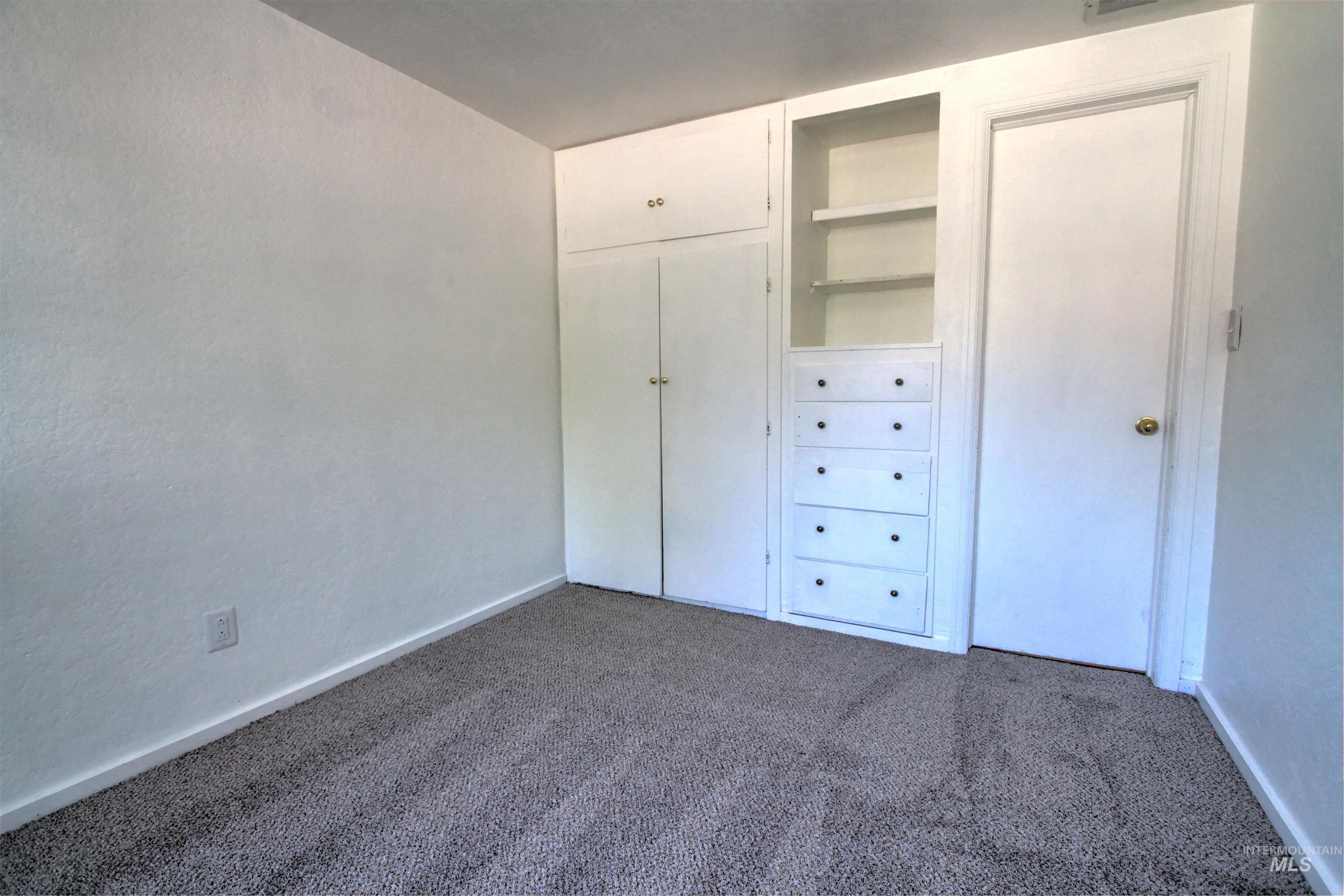 Unfurnished bedroom featuring dark carpet and a closet