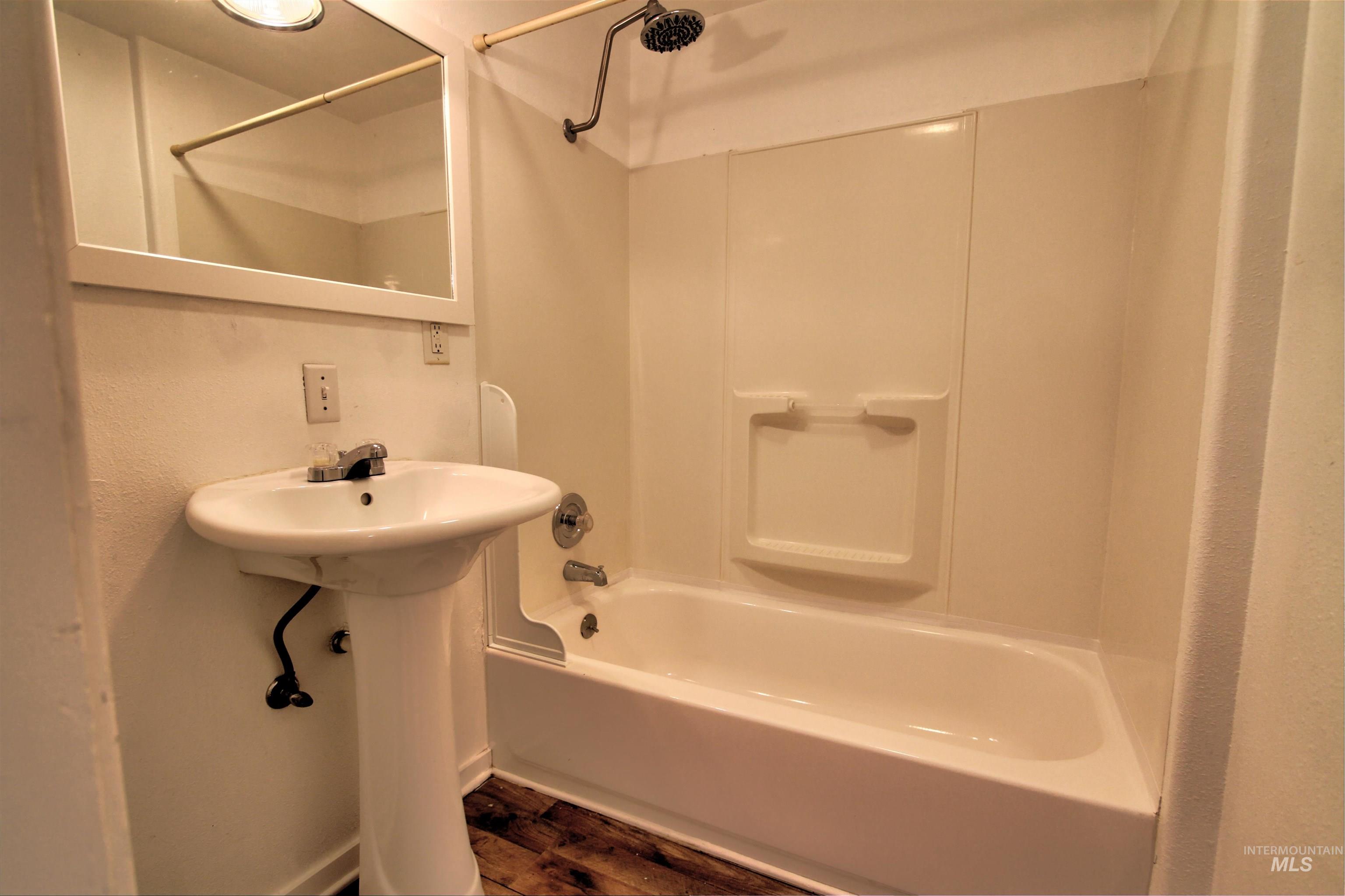 Bathroom featuring shower / bath combo with shower curtain and dark wood-style flooring