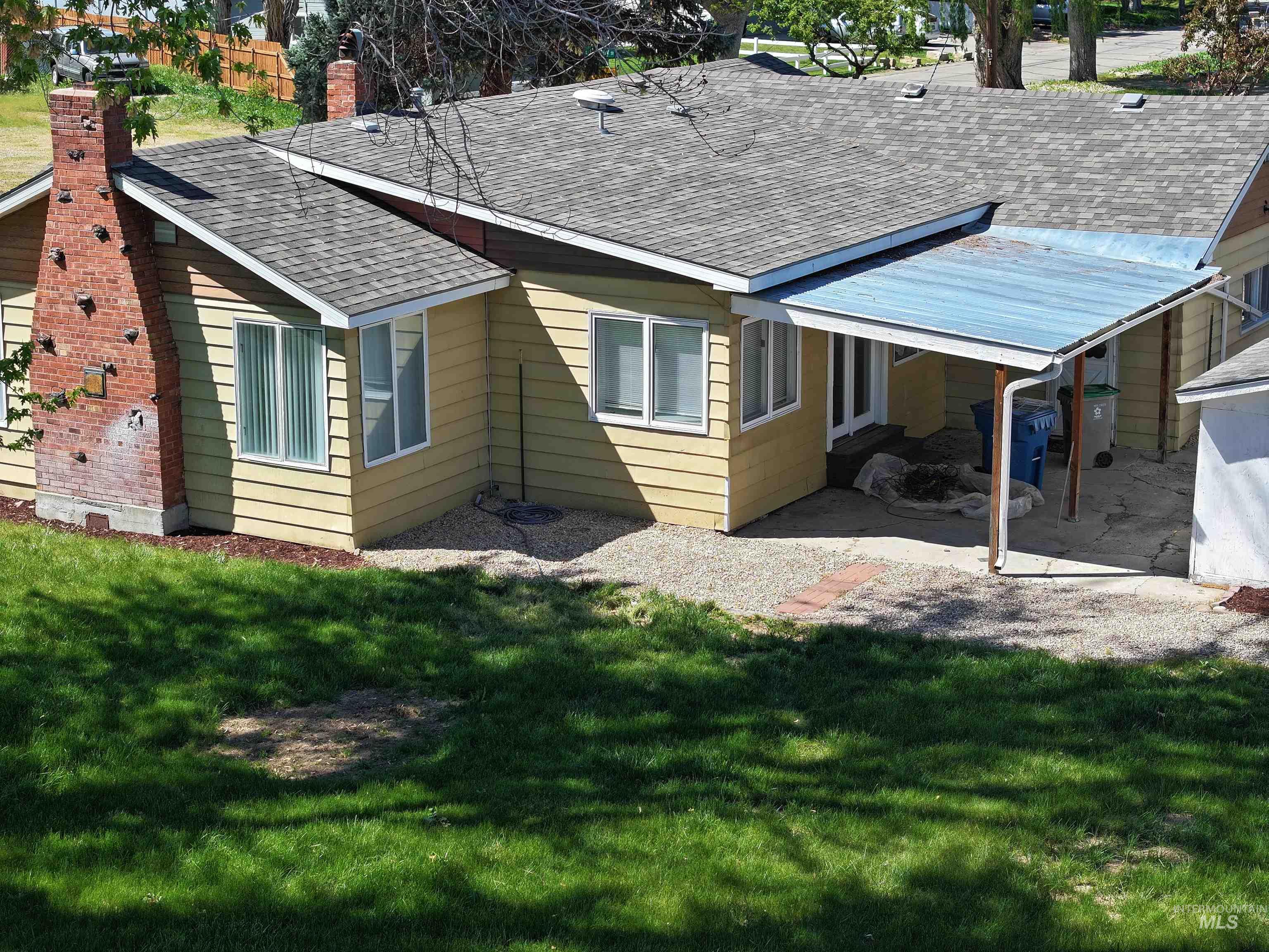 Rear view of house featuring roof with shingles, a lawn, and a chimney
