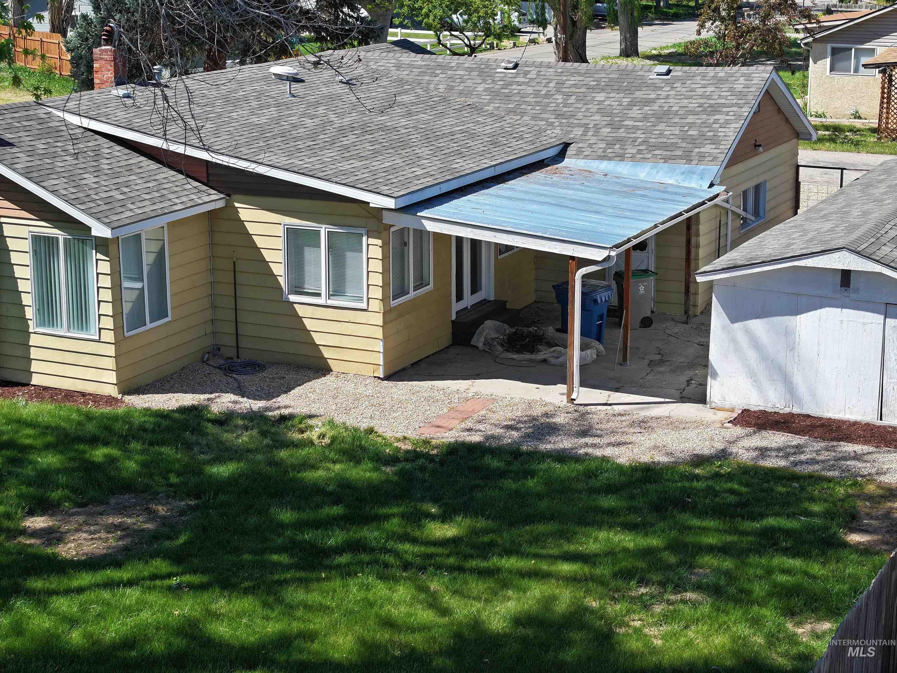 Back of house with a shingled roof, a lawn, and a chimney