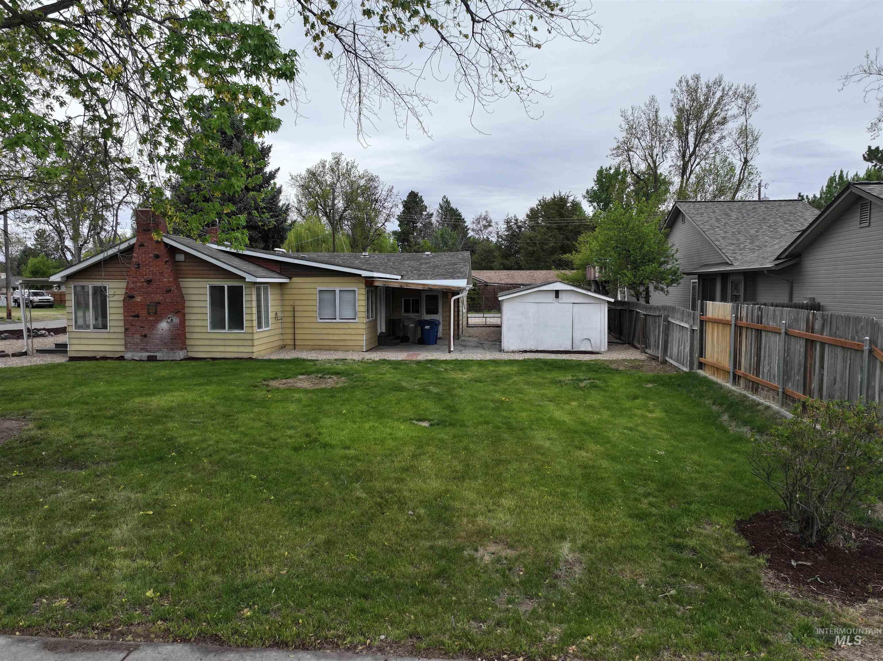 Back of house with a patio, a shed, a fenced backyard, a chimney, and view of scattered trees
