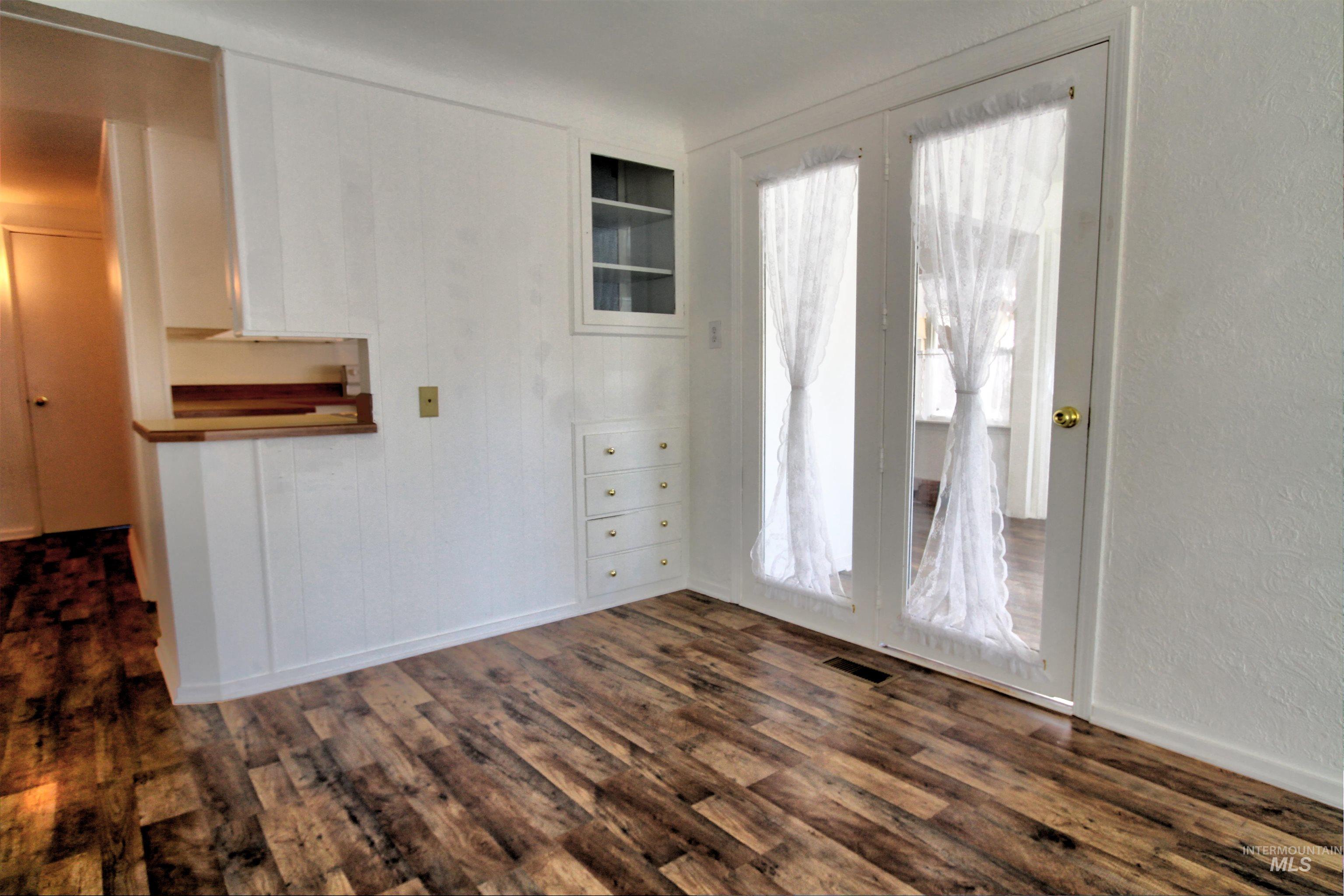 Unfurnished room with dark wood-type flooring and a textured wall